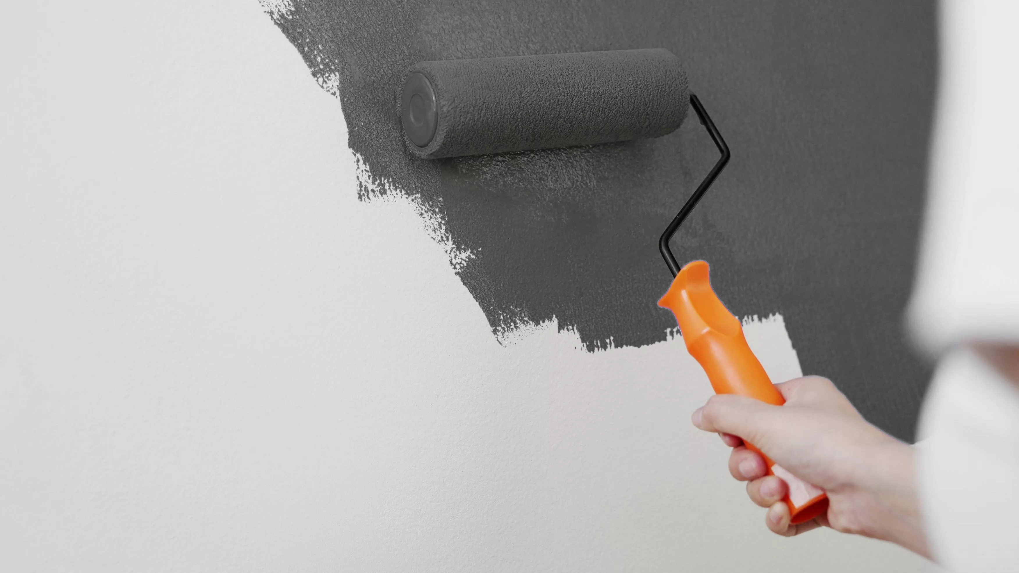 Grüne Farbe wird mit einem Farbroller auf einer Wand aufgetragen